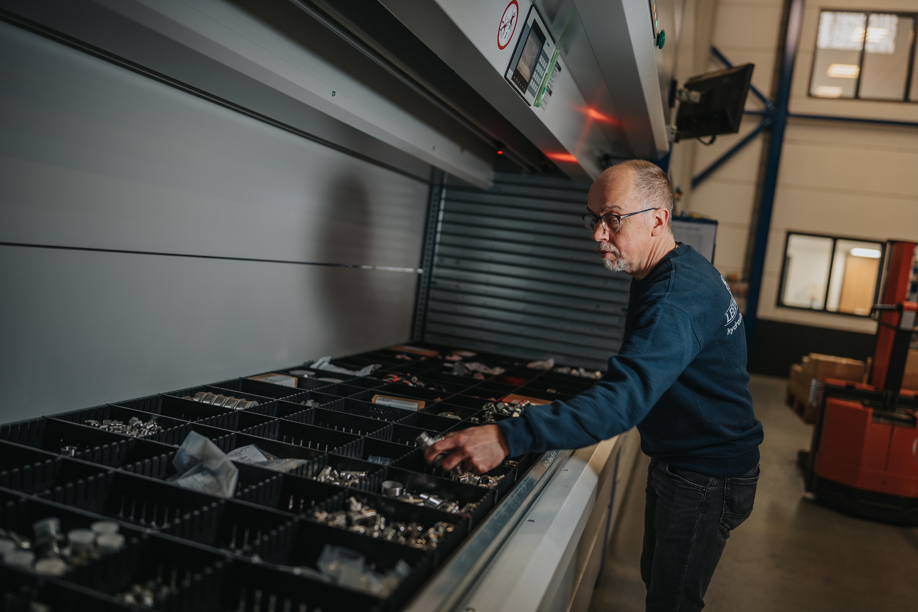 Medewerker van Leeuwtechniek haalt slangkoppelingen uit een Kardex-kast