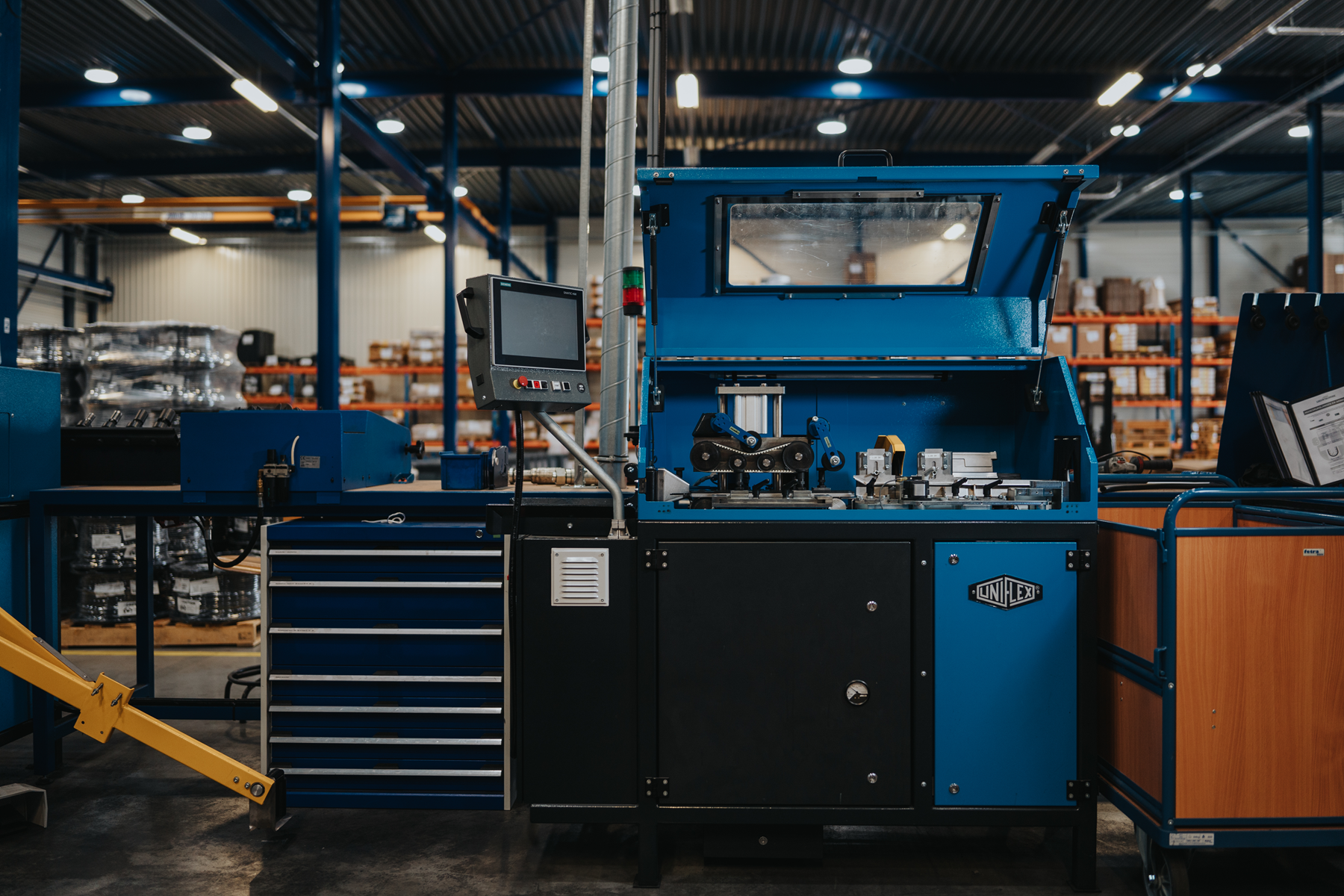Medewerker van Leeuwtechniek bij de volautomatische productielijn met UNIFLEX-slangensnijmachine